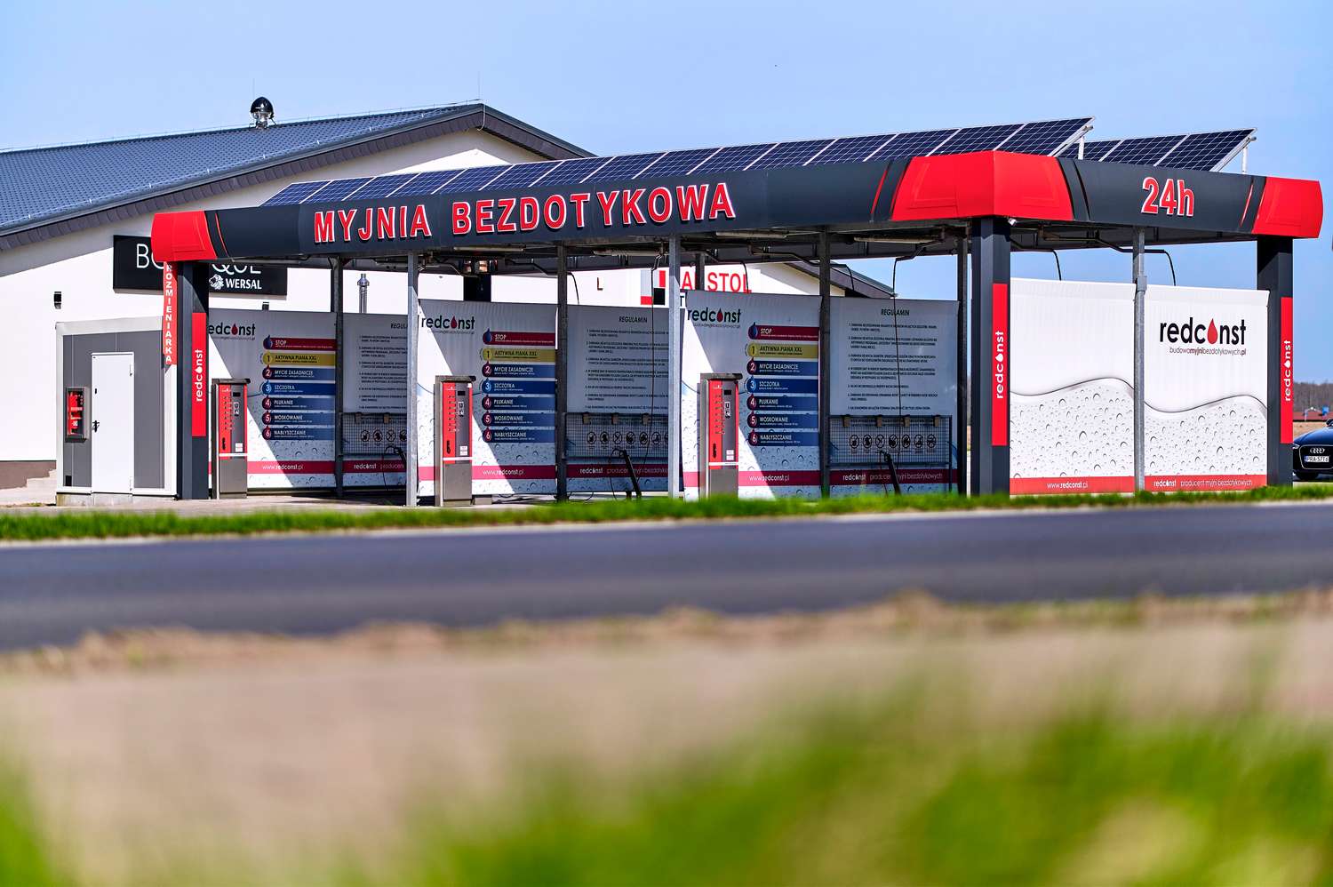 Nowoczesna myjnia bezdotykowa z panelami słonecznymi, dostępna 24h, z różnorodnymi programami czyszczenia. Znajduje się w malowniczej okolicy, przy drodze, oferując wygodny dostęp dla użytkowników. Idealne rozwiązanie dla osób szukających efektywnego mycia samochodu.