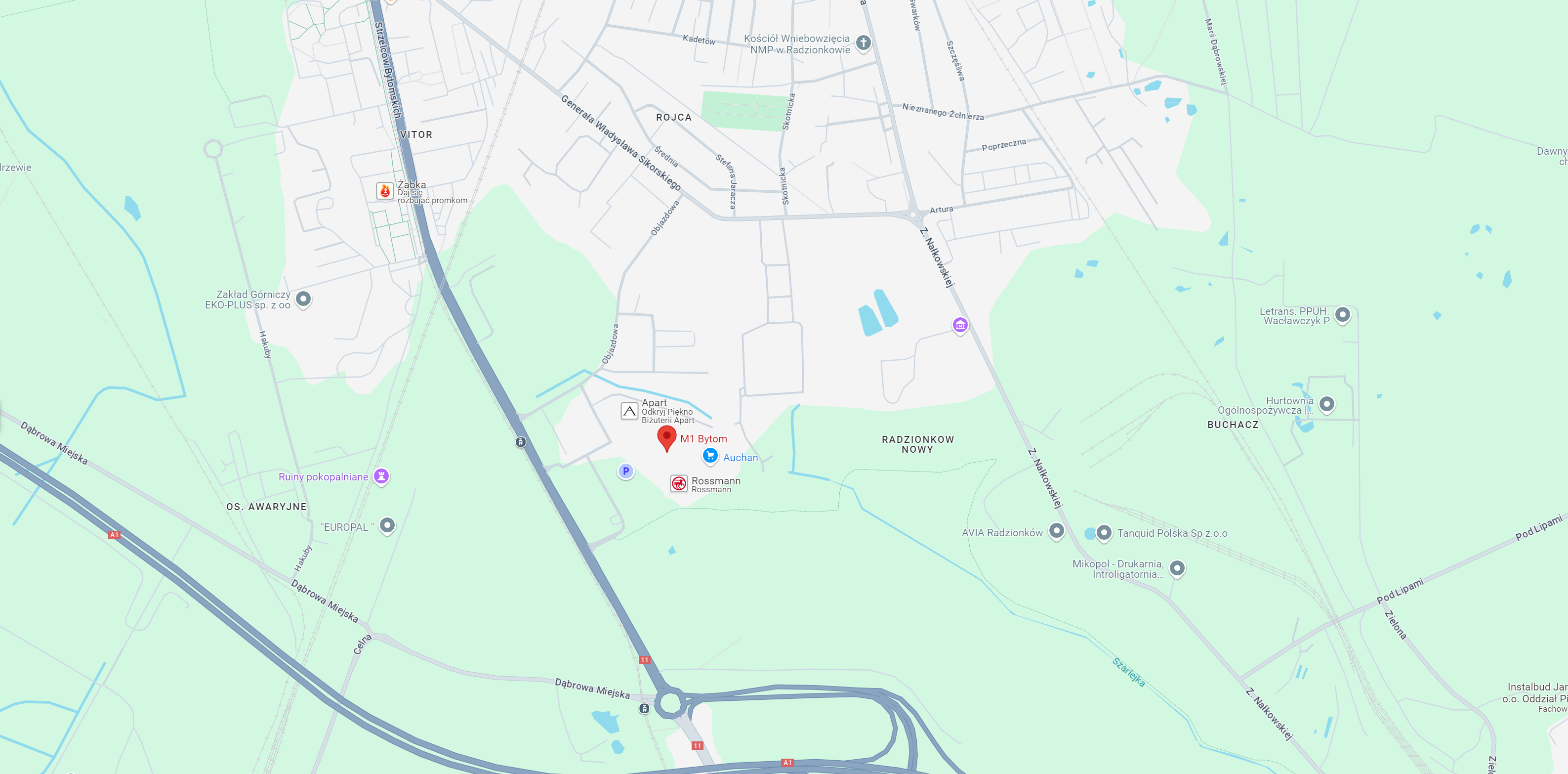 Mapa przedstawiająca obszar wokół M1 Bytom, z oznaczeniem lokalizacji Auchan, Rossmann oraz innych punktów, takich jak Zakład Górniczy EKO-PLUS i Ruiny Pokopalniane. Widoczna jest również infrastruktura drogowa w okolicy miasta Radzionków.